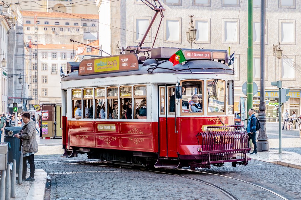 Red Lisbon tram on a city tour passing through a lively urban square
