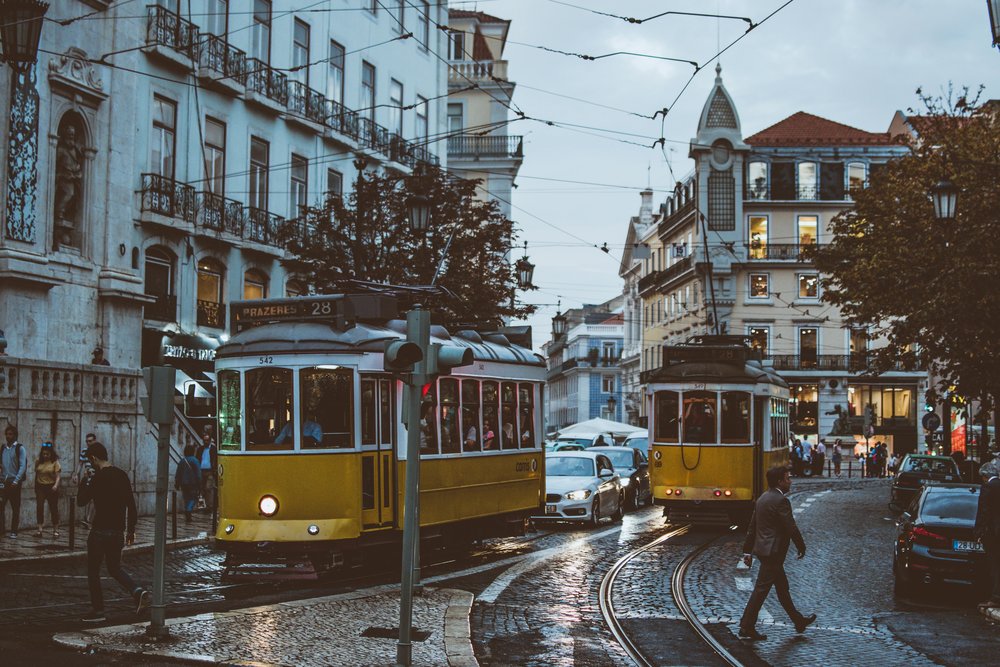 Yellow Tram 28 moving through Lisbon’s evening streets after rain.