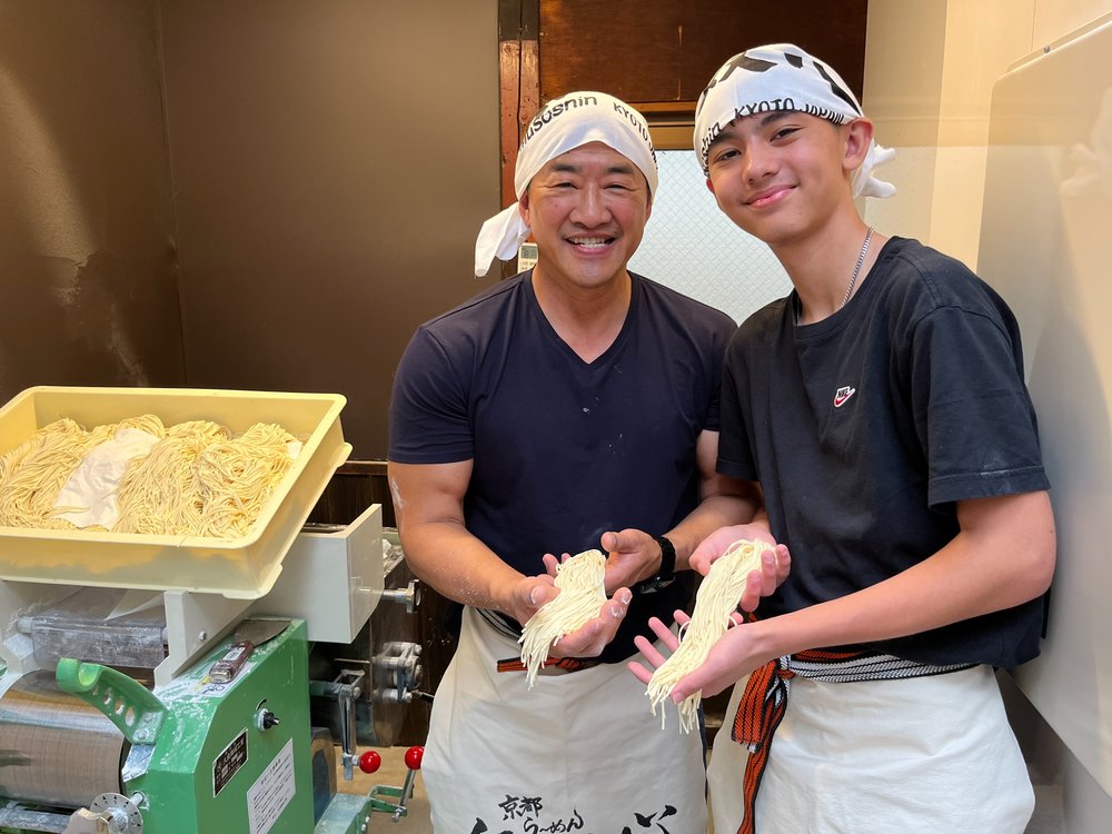 Two people holding freshly made ramen noodles