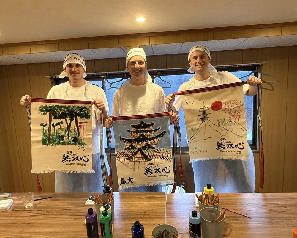 Three people holding their newly painted aprons
