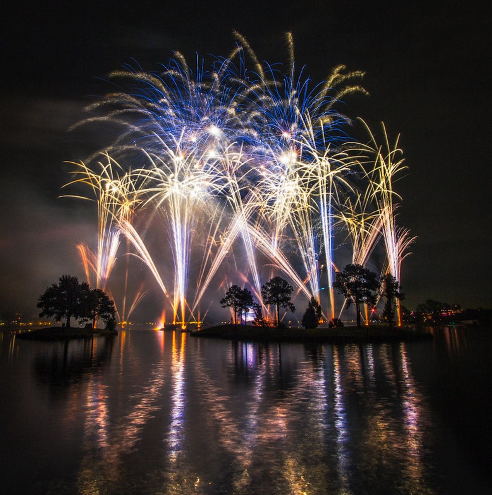 Bright fireworks display illuminating the night sky over an Orlando lake