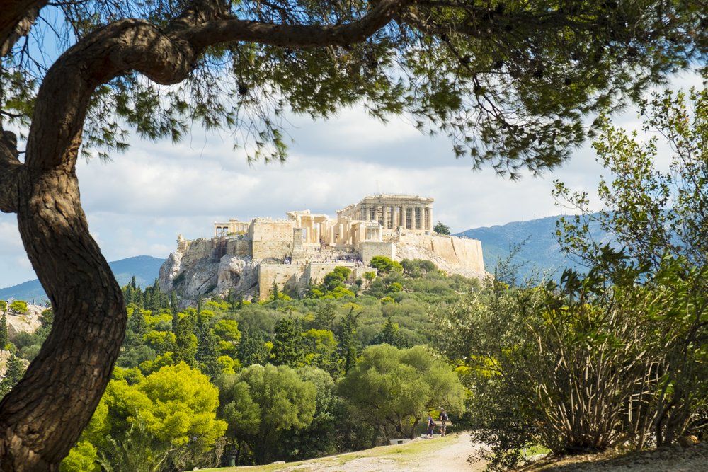 Acropolis of Athens seen from Filopappou Hill through green trees