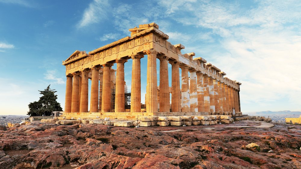 Parthenon temple in Athens lit by sunlight against a blue sky