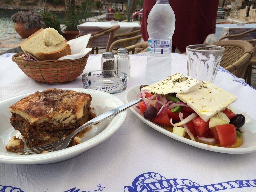 Plate of moussaka and Greek salad at an outdoor taverna in Greece