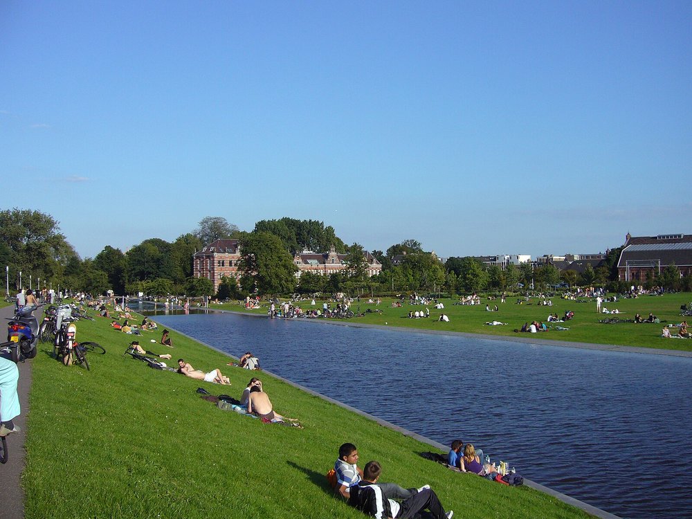 People lounging by the waterfront lawn in Westerpark Amsterdam