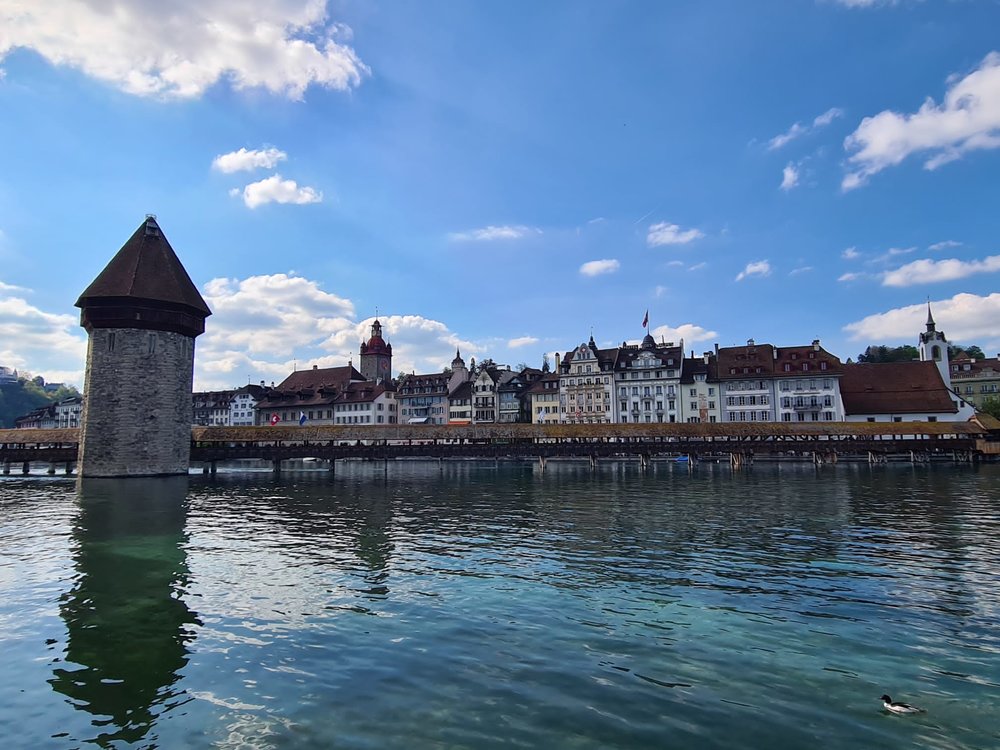 Chapel Bridge and stone Water Tower with their reflections on Lake Lucerne