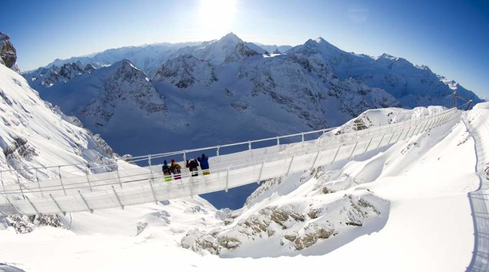 A small group of people crossing the Cliff Walk, with the Alps surrounding them