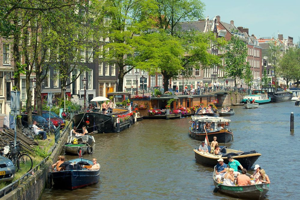People boating along Amsterdam’s lively canals on a bright summer afternoon