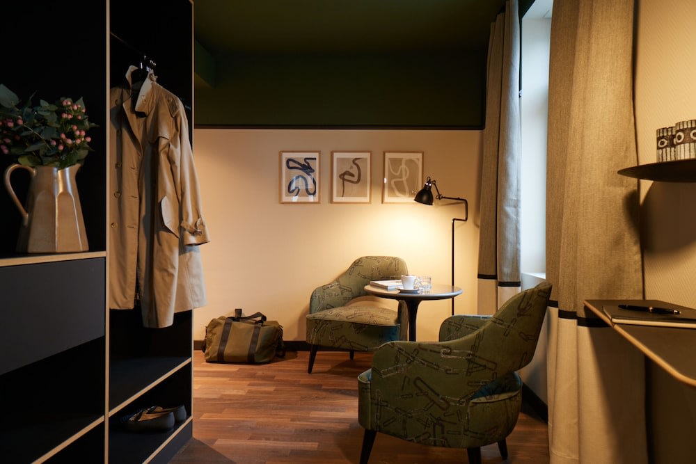 The hotel room’s small living room area that has two chairs, an open closet, and a window