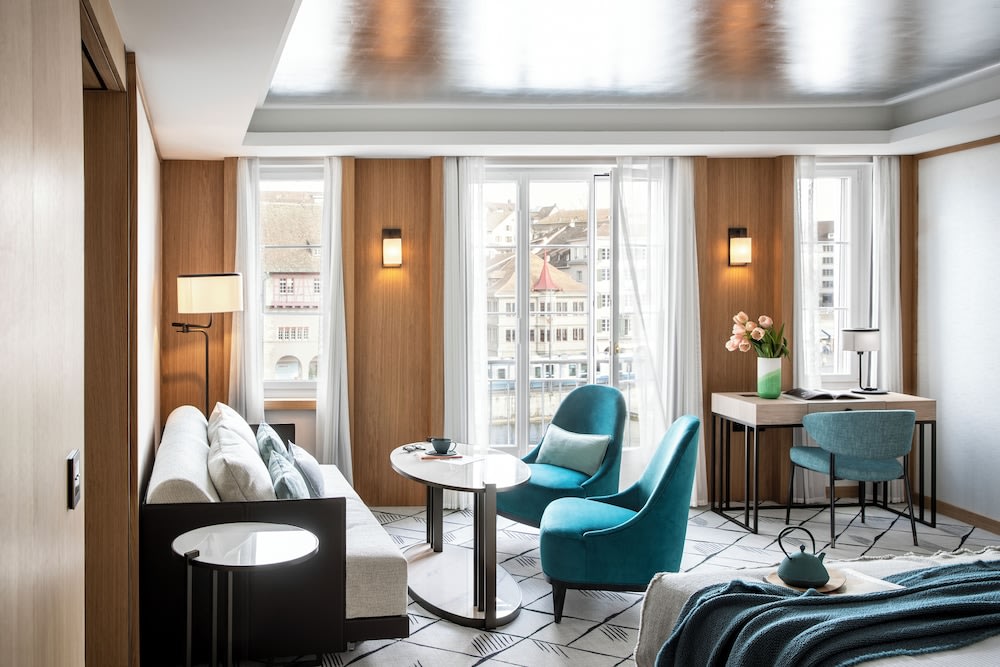 A spacious hotel room, with a sofa and a study desk at the foot of the bed