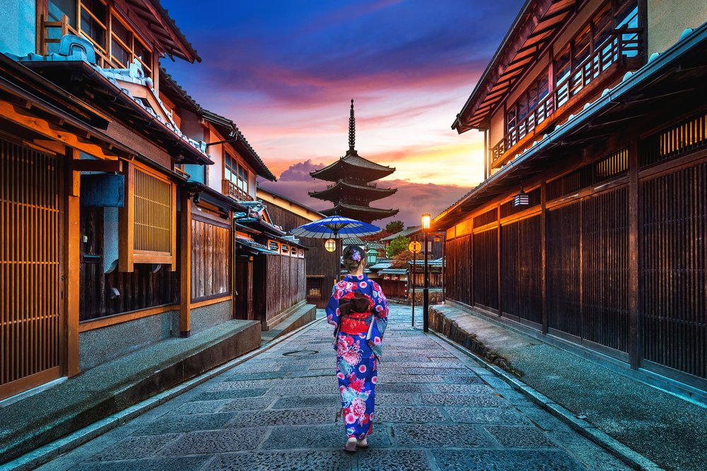 Woman in kimono walking toward Yasaka Pagoda at sunset in Gion