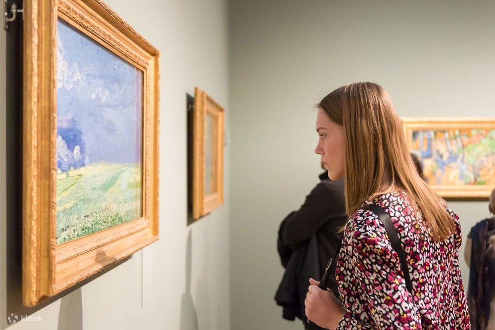 A woman observing a colorful painting at the Van Gogh Museum.