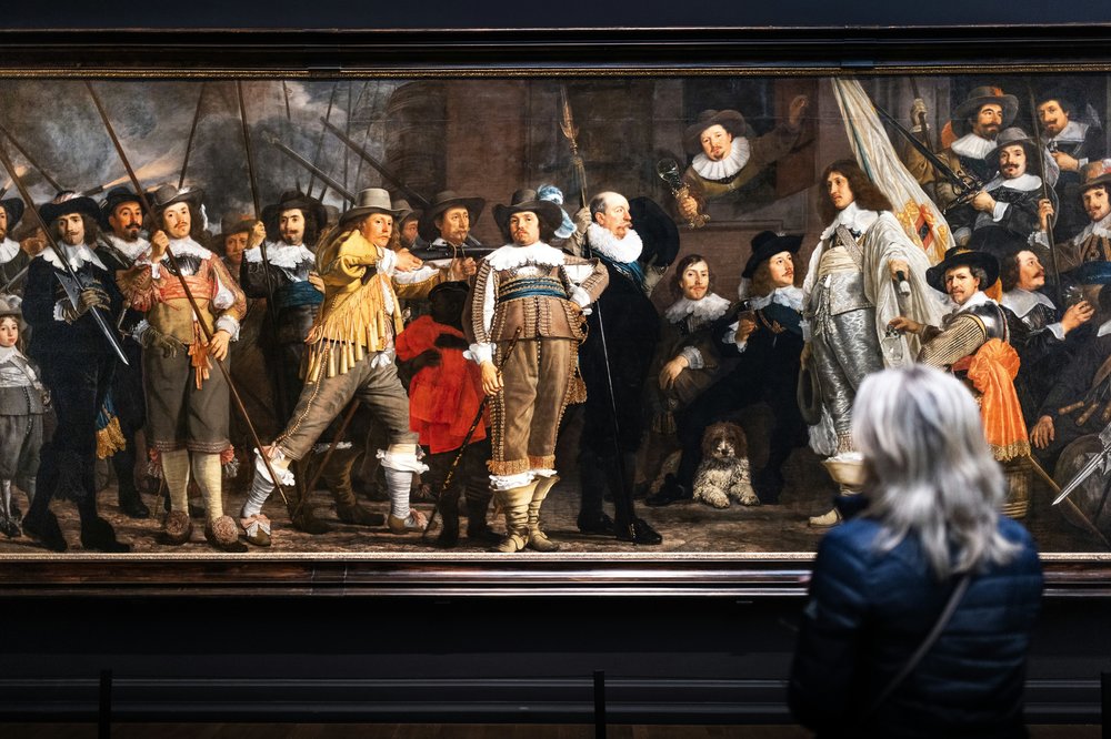 A woman admiring a painting at the Rijksmuseum.