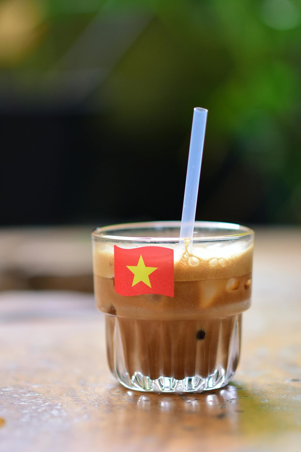 A cup of Vietnamese iced coffee with a flag of Vietnam printed on its glass.