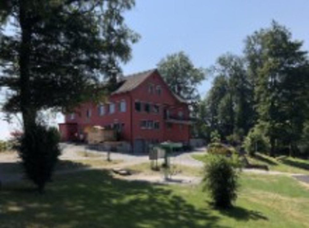 An outside view of Restaurant Felsenegg’s rustic building exterior with hiking signs.