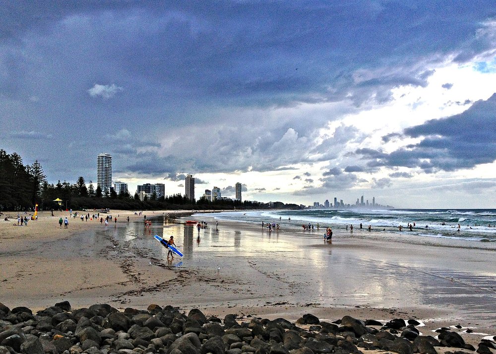 People walking along Burleigh Heads Beach with ocean waves and Gold Coast skyline in view