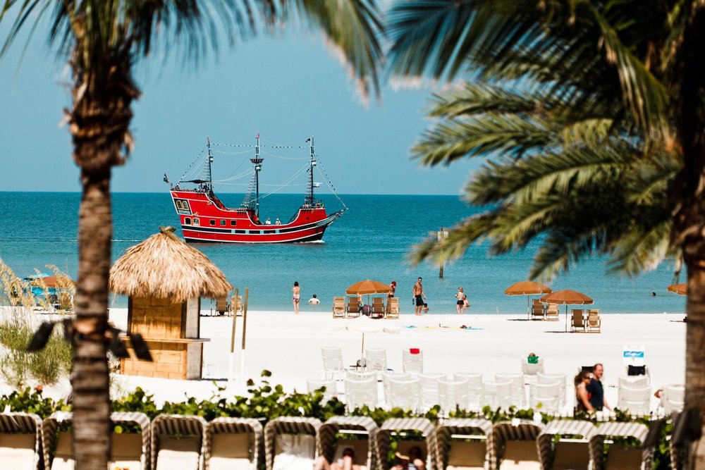 Red pirate ship off Clearwater Beach with white sand and palm trees