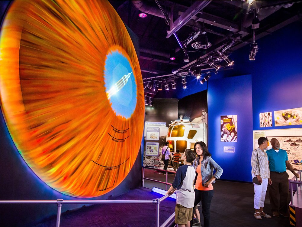 Visitors viewing colorful space exhibits inside Kennedy Space Center