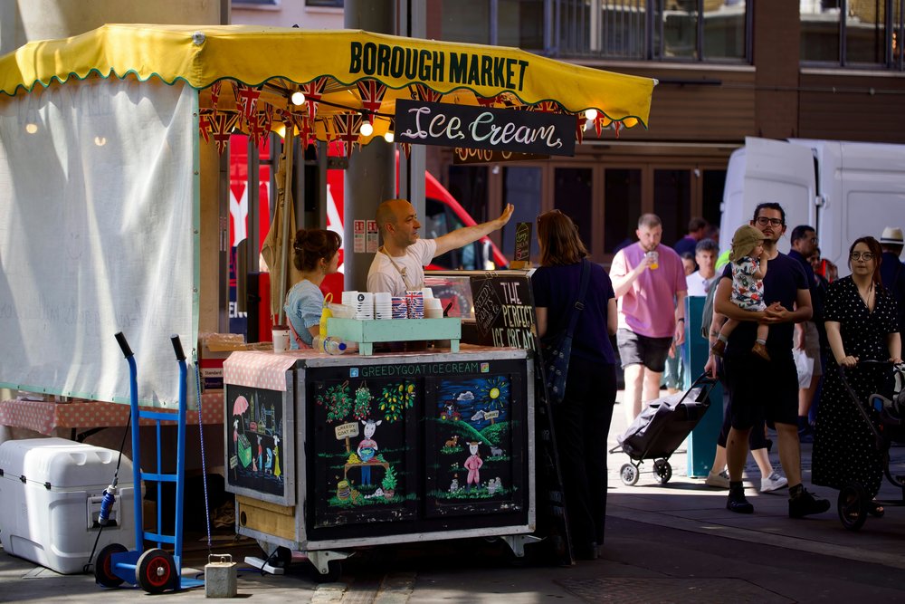 Borough Market food stall in London with ice cream stand and visitors browsing.