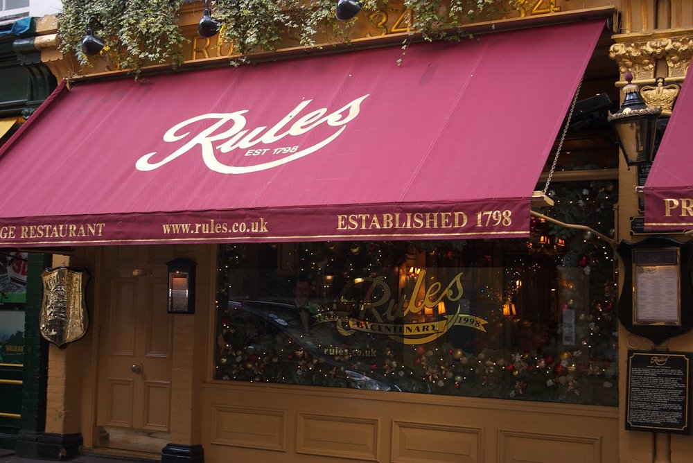 Exterior of Rules restaurant in London with red awning and historic signage