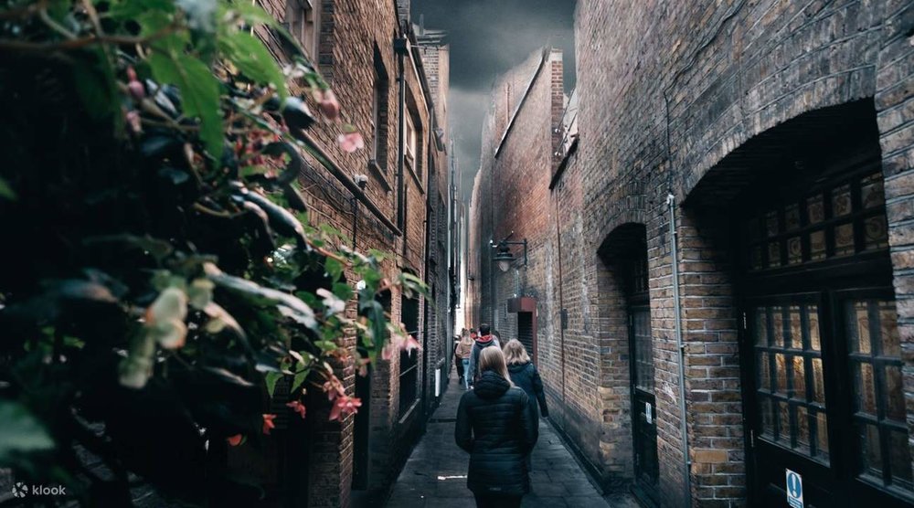 Visitors walking through a narrow brick alley in London inspired by Harry Potter filming locations