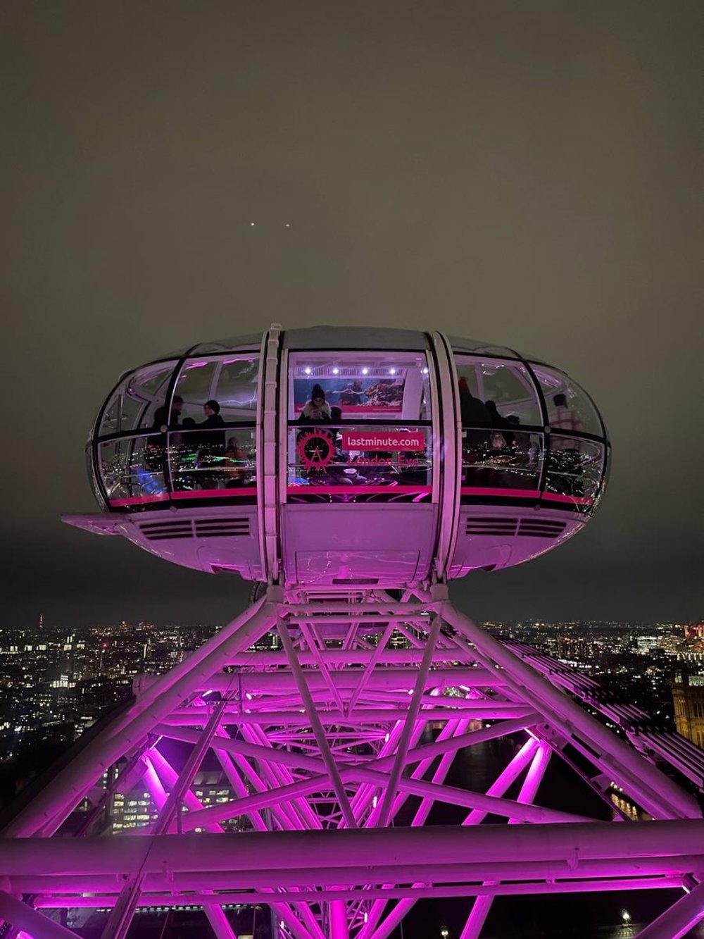 London Eye capsule lit at night with city lights below