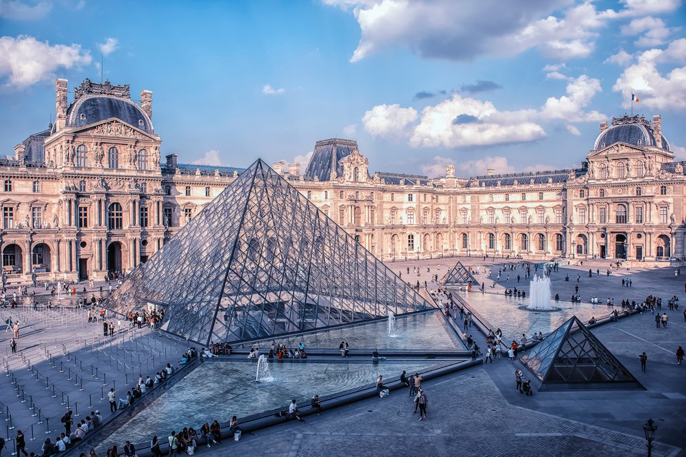 Louvre Museum courtyard with glass pyramid and historic palace buildings