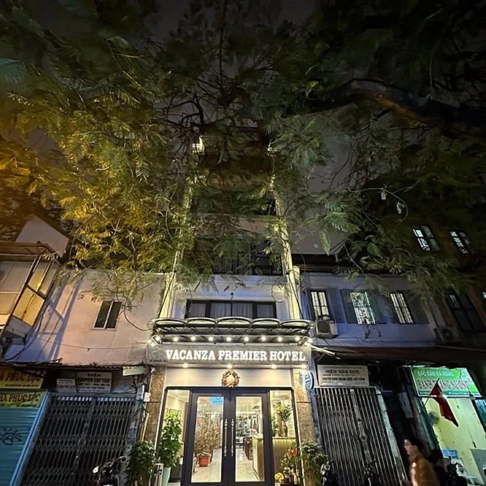 Hanoi Vacanza Premier Hotel exterior at night on a lively Old Quarter street