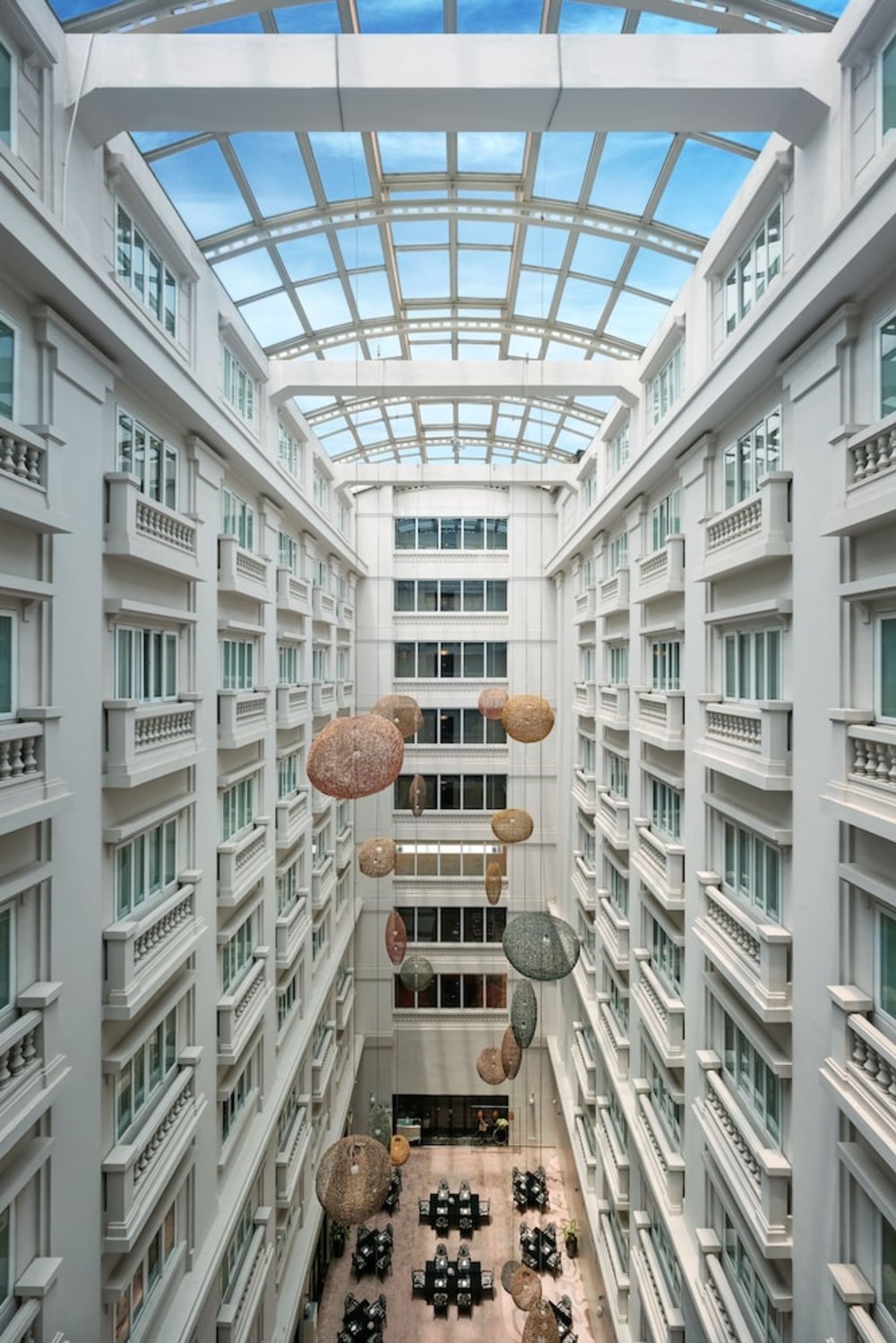 Hotel atrium in Hanoi with glass ceiling, white balconies, and open central space