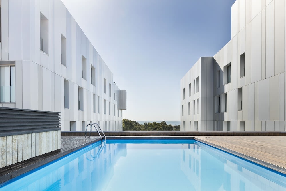 A pool surrounded by apartments overlooking the sea