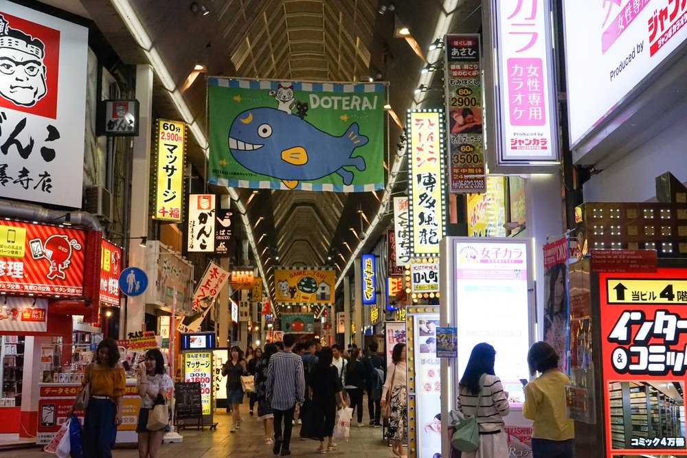 Crowded Shinsaibashi-suji Shopping Arcade with bright signs and shops in Osaka