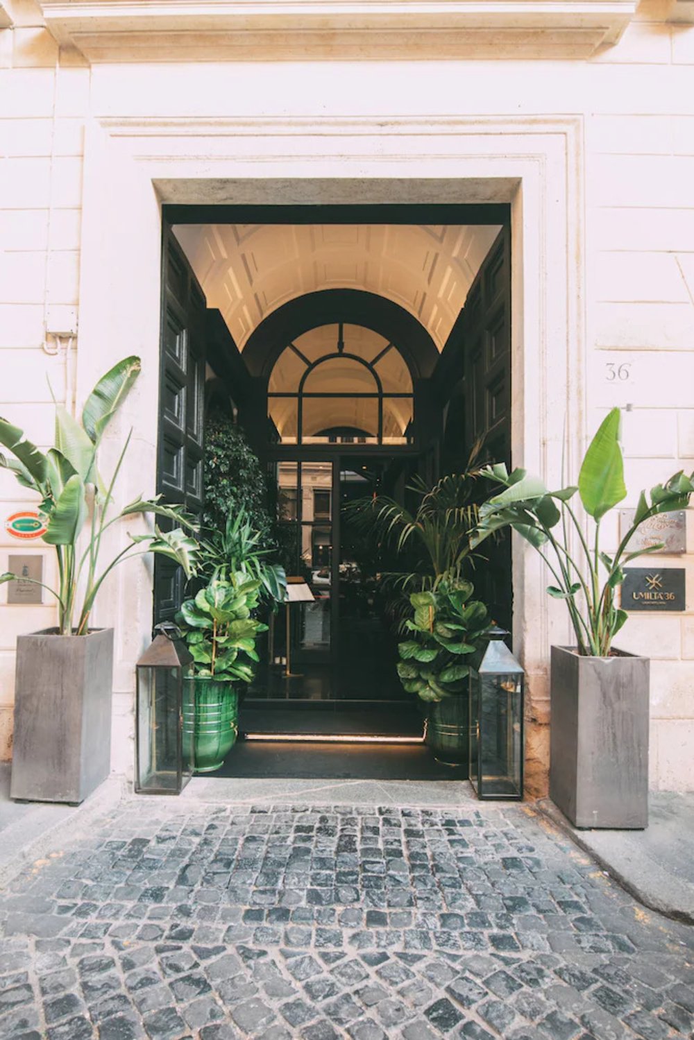 Entrance of a Rome city center hotel with greenery and arched doorway