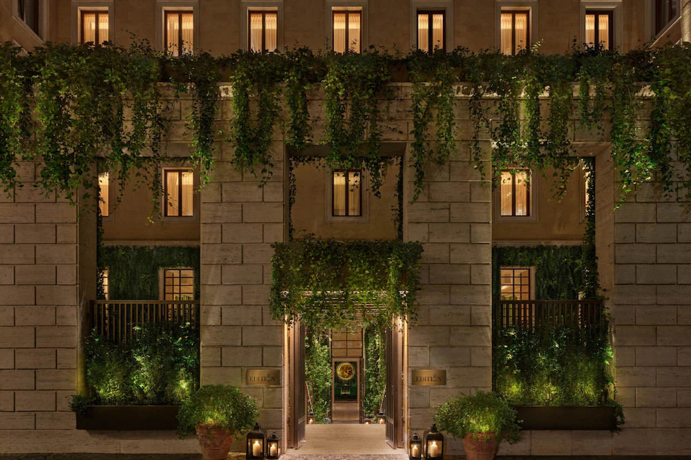 Luxury hotel building in Rome with lit windows and green facade at night