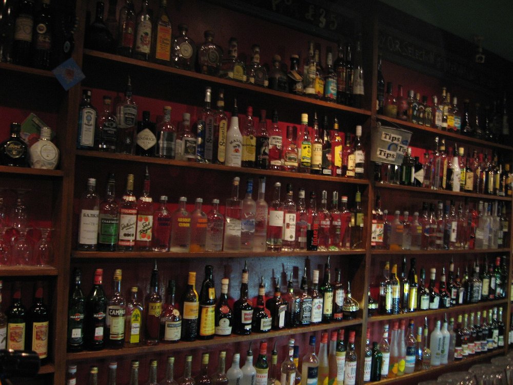 Shelves filled with liquor bottles behind the bar in a traditional UK pub