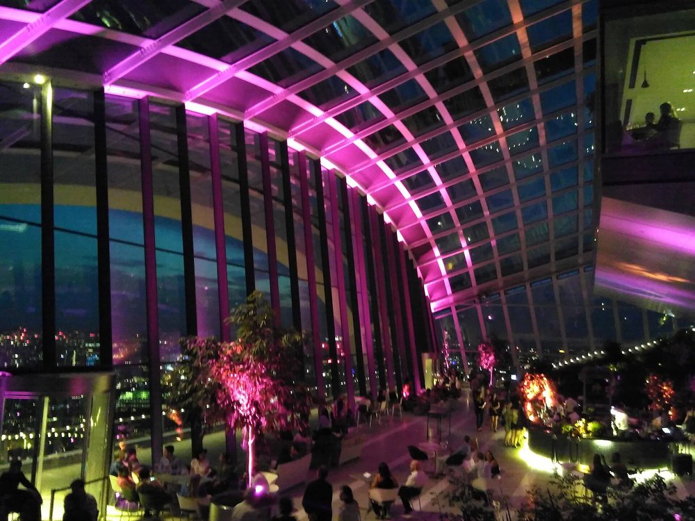 People enjoying drinks at Sky Garden rooftop bar in London with city views