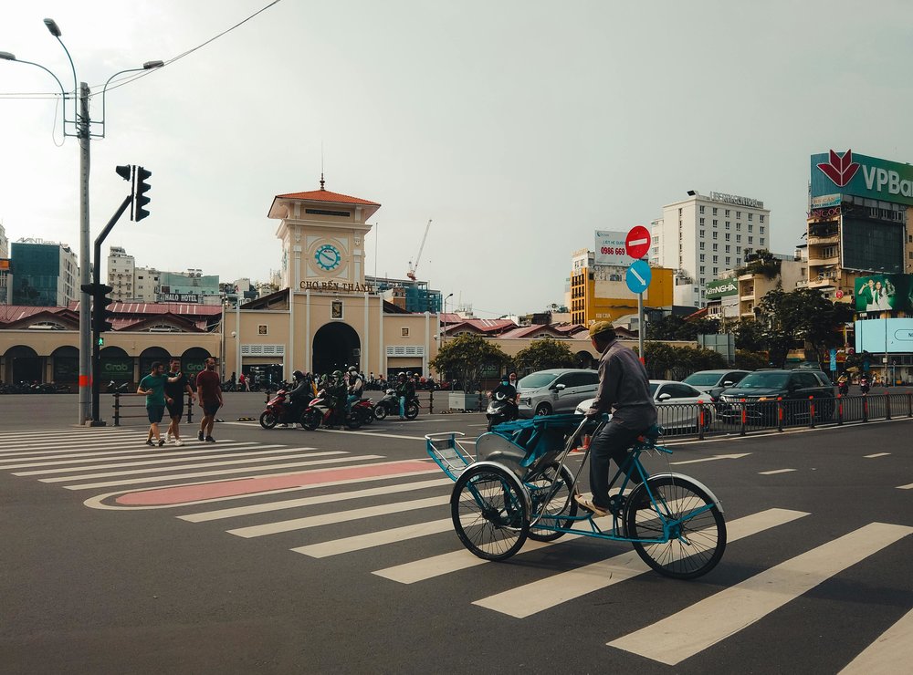 Ben Thanh Market Ho Chi Minh City with cyclists, motorbikes, and city streets