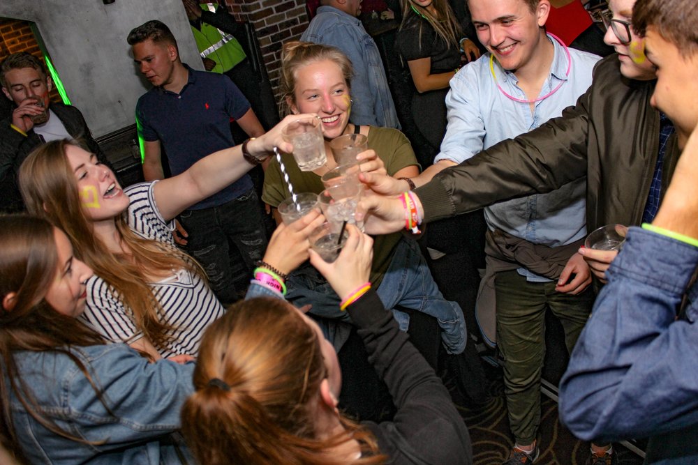 Group of young adults cheering with drinks inside a busy Sydney bar at night