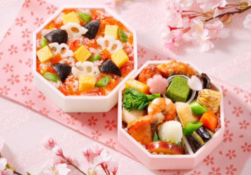 A hanami bento with shrimp, fruits, onigiri, and more.