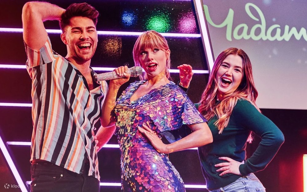 Visitors pose beside the Taylor Swift wax figure inside Madame Tussauds