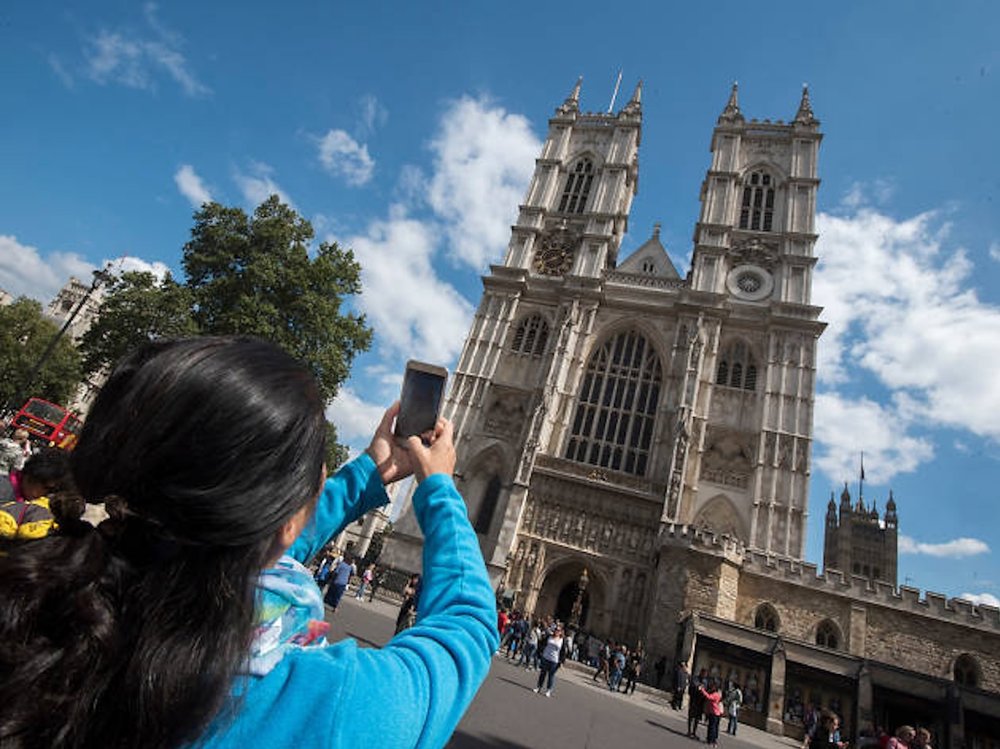 Visitor taking photos outside Westminster Abbey in London on a sunny day