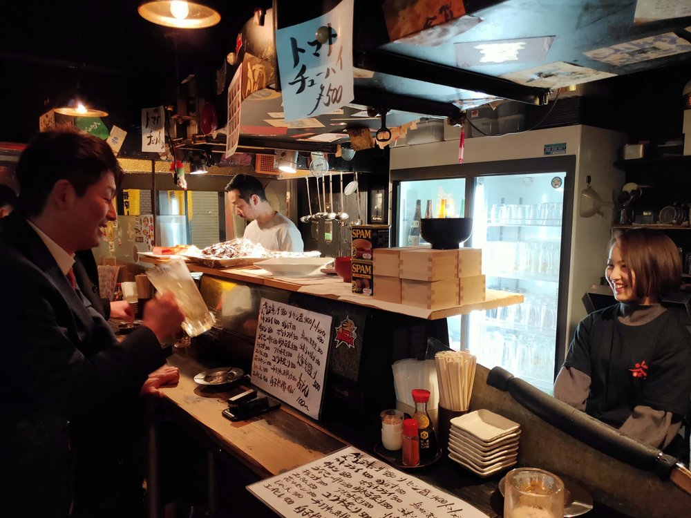 People enjoying drinks at a cozy Japanese izakaya bar in Hiroshima 