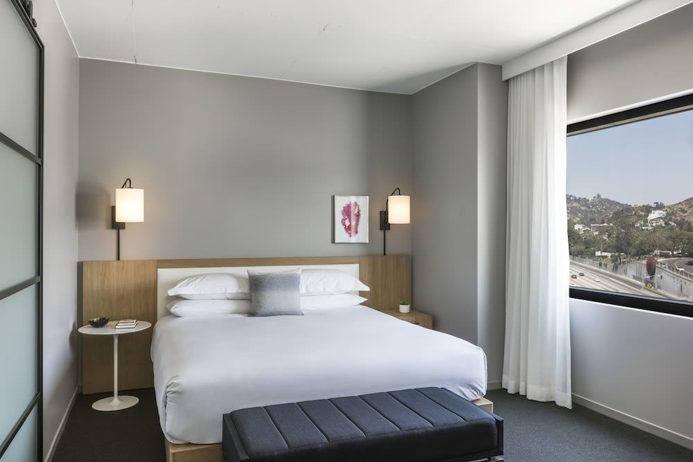 Minimalist hotel room in Los Angeles with a large bed and window view