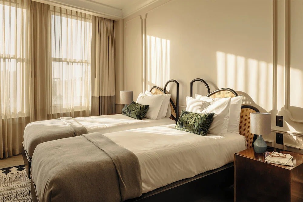 Twin-bed boutique hotel room with soft decor and large windows in LA