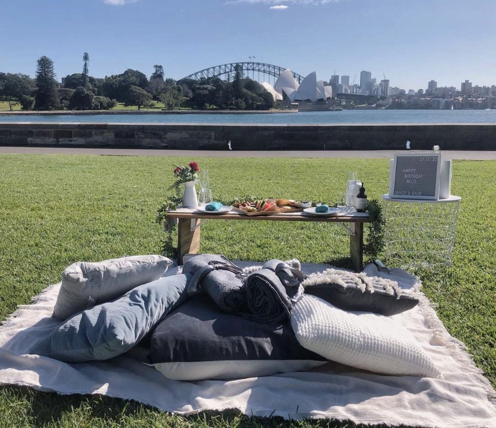 Picnic setup on grass with Sydney Opera House and Harbour Bridge in the distance