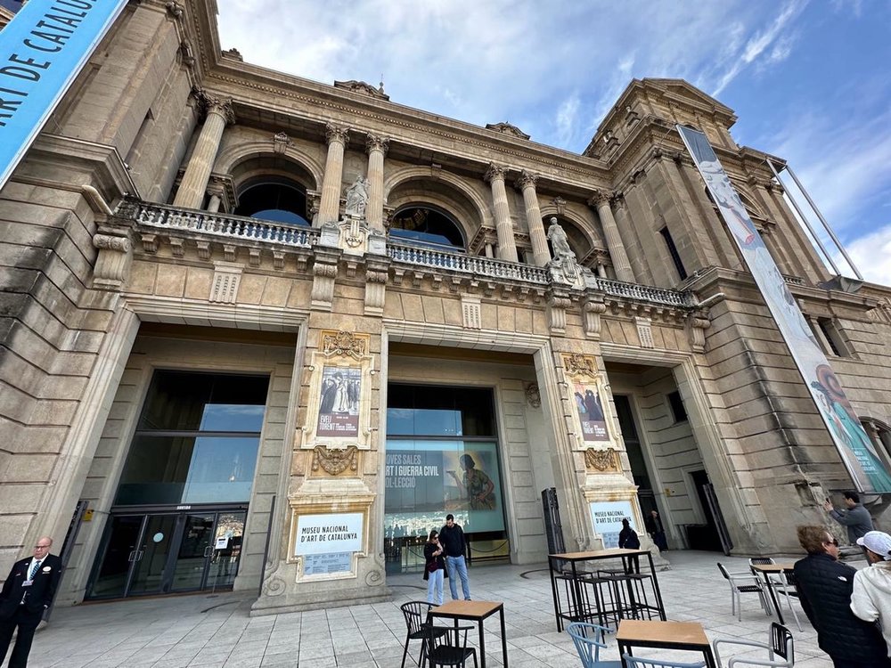 Exterior entrance of the National Art Museum of Catalonia in Barcelona with columns and visitors outside.