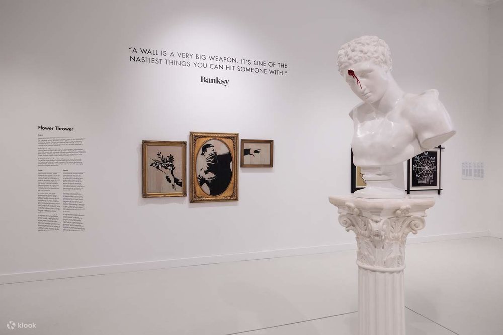 White classical-style sculpture and framed modern artworks displayed in Moco Museum.
