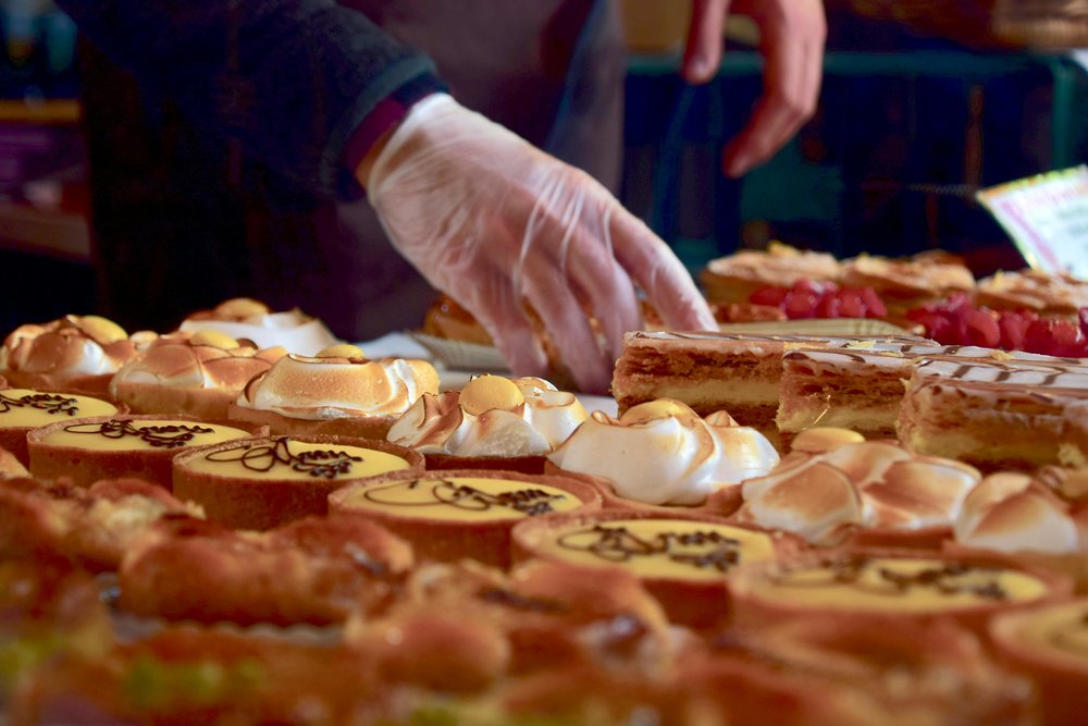 Hand selecting pastries and cakes at a dessert counter in Orlando