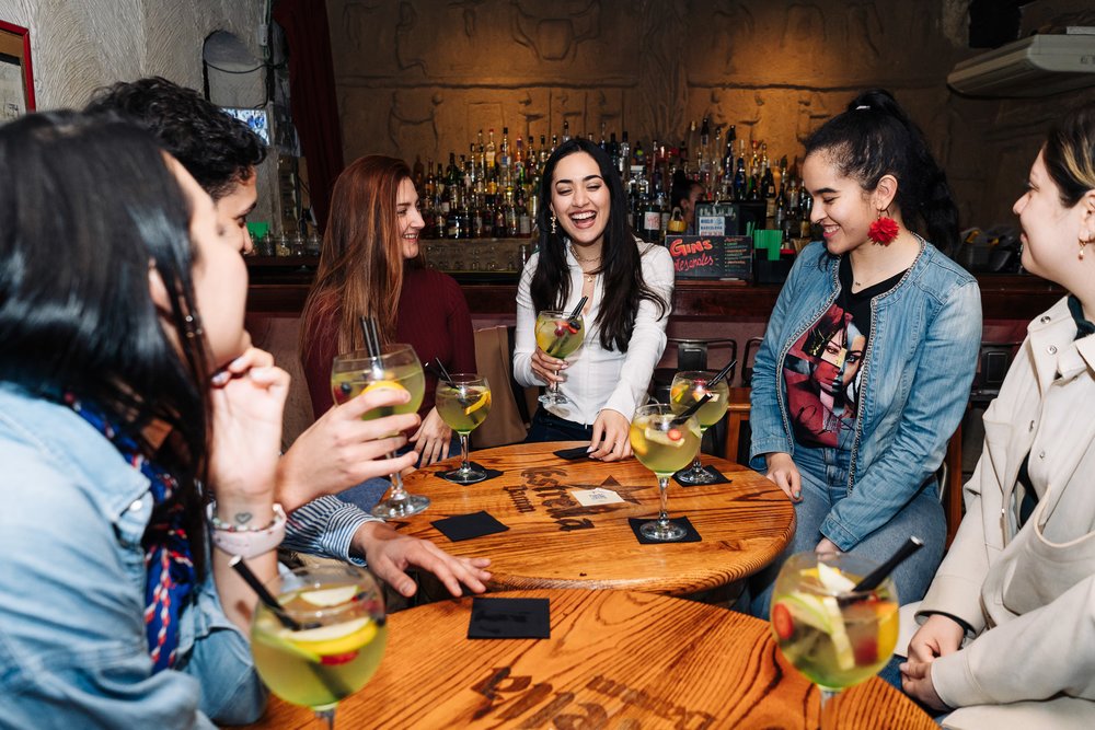 Group of friends sipping cocktails at a lively neighborhood bar in Barcelona