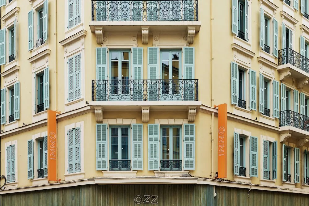 Exterior view of Hostel Ozz Nice with balconies and pastel shutters in central Nice