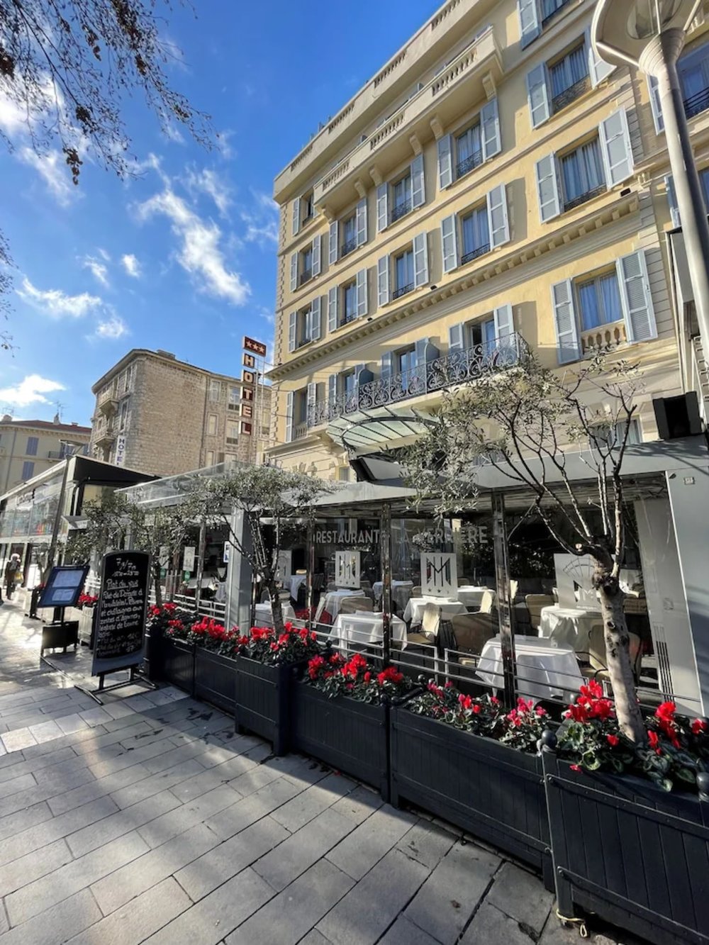 Hotel and restaurant terrace along a sunny street in central Nice, France